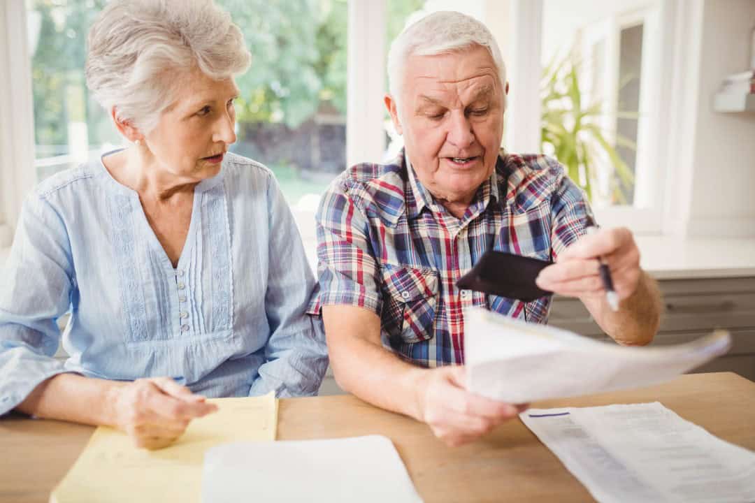 Worried senior couple checking their bills at home