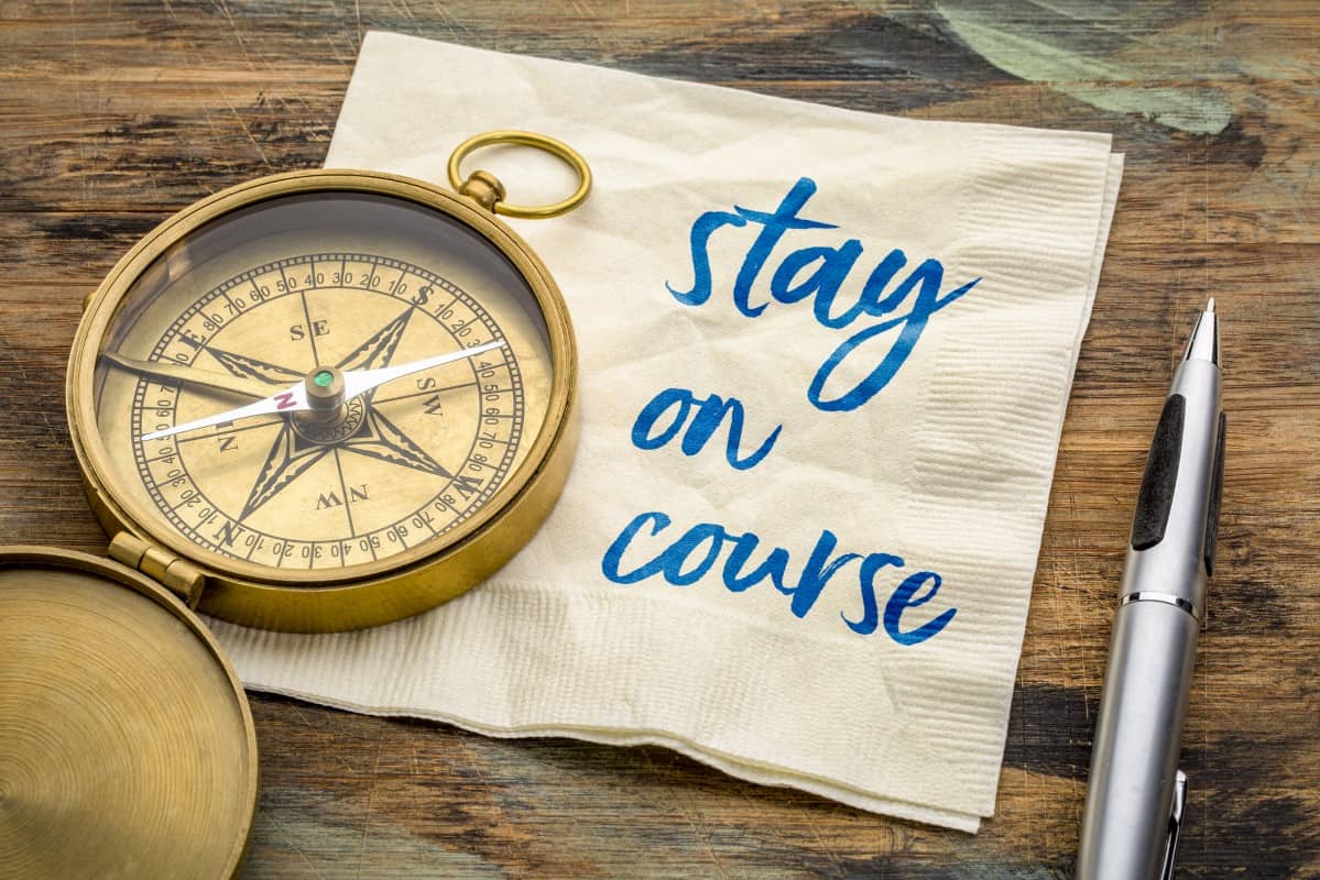 Stay on course reminder - motivational handwriting on a napkin with an antique brass compass, navigation, determination and setting goals concept