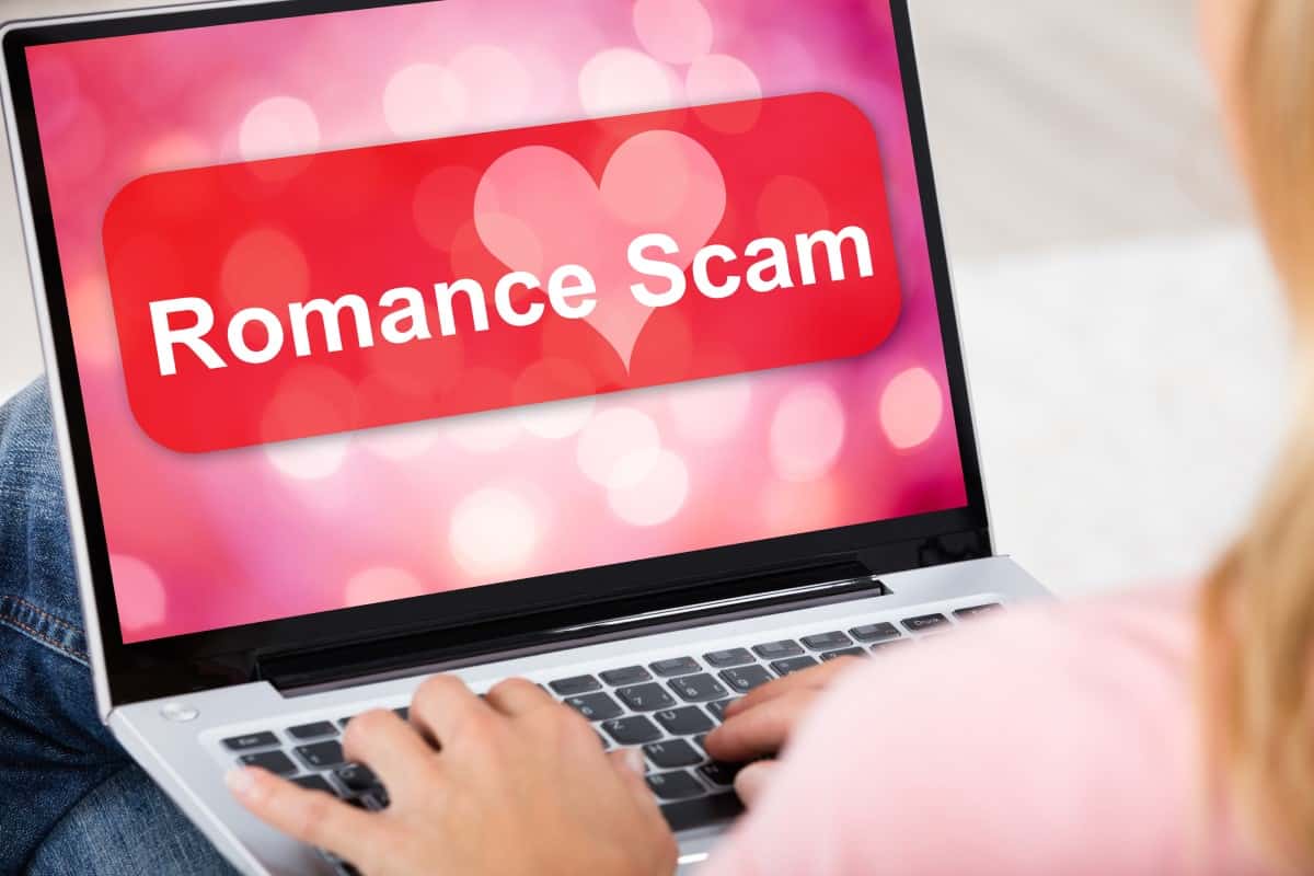 Close-up Of A Woman Using Laptop With Romance Scam Application On Screen Sitting At Home