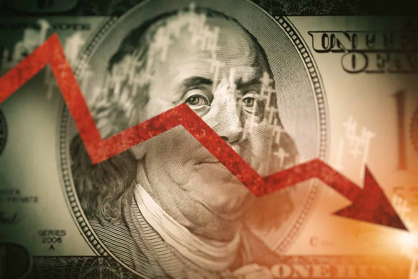 Closeup detail of dollar bill. Economist forecast for the United States. Glowing red arrow going downwards on Benjamin Franklin portrait on dollar.. Effect of coronavirus on US economy and recession concept.