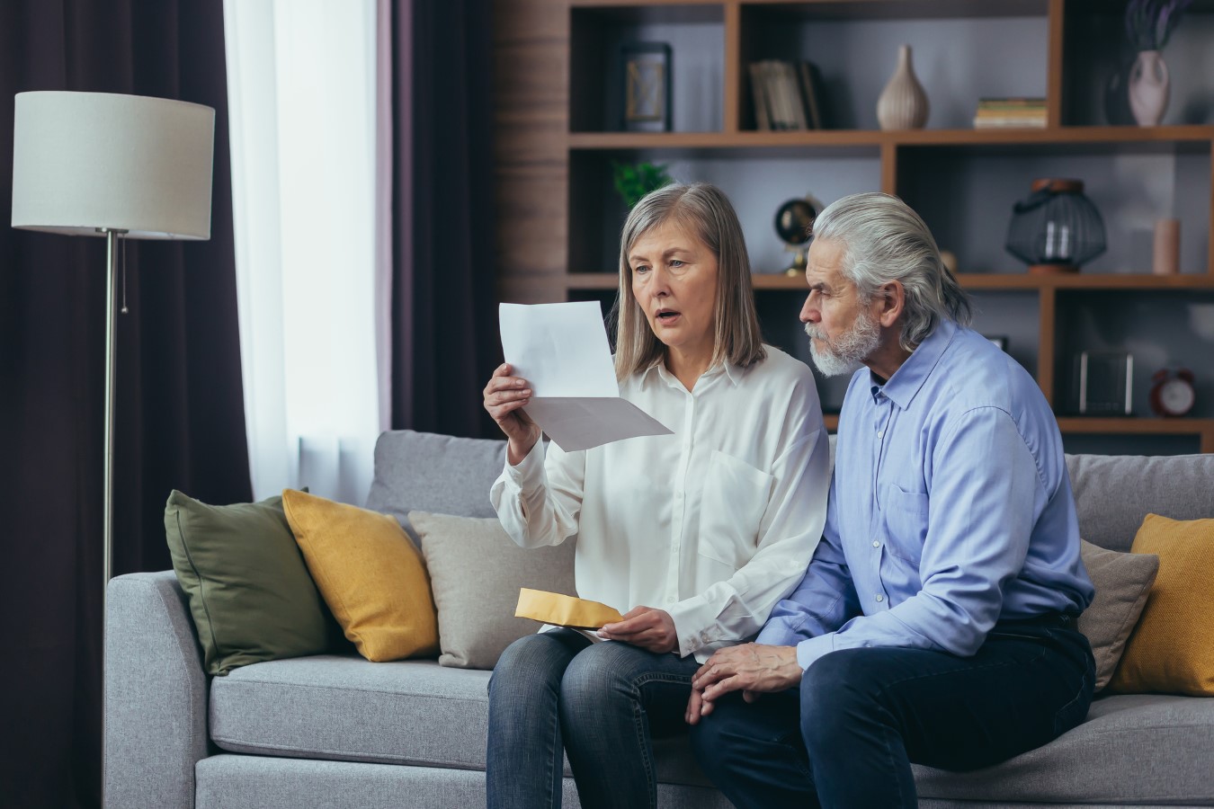 Angry frustrated document senior couple. Unhappy old family getting stressed. Serious older husband showing banking paper document bills taxes to confused elderly wife in home. Worried looking utility