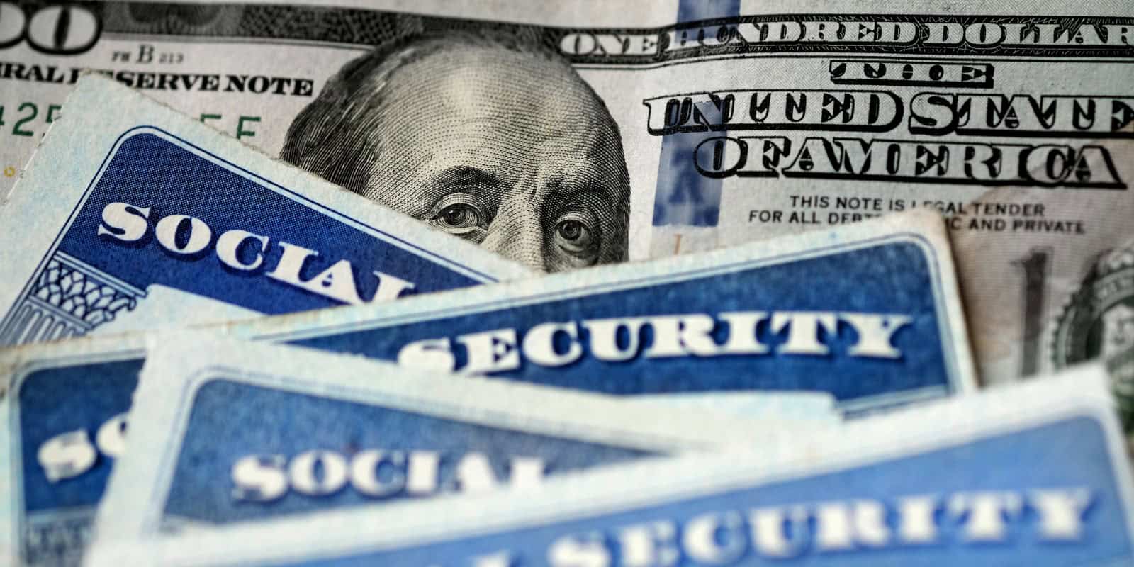 Several Social Security Cards on a US United States one hundred dollar bill $100 system of benefits for retired elderly people