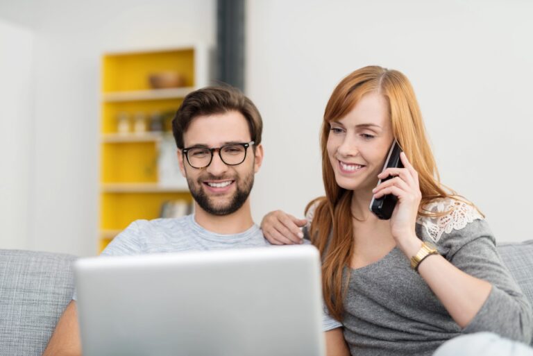 Couple with Laptop and Telephone Sitting on Sofa