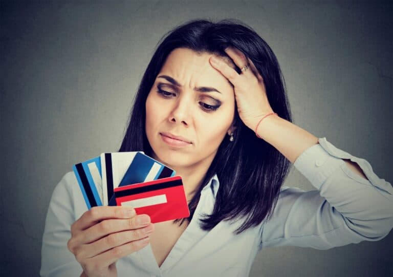 Stressed woman in debt holding at multiple credit cards