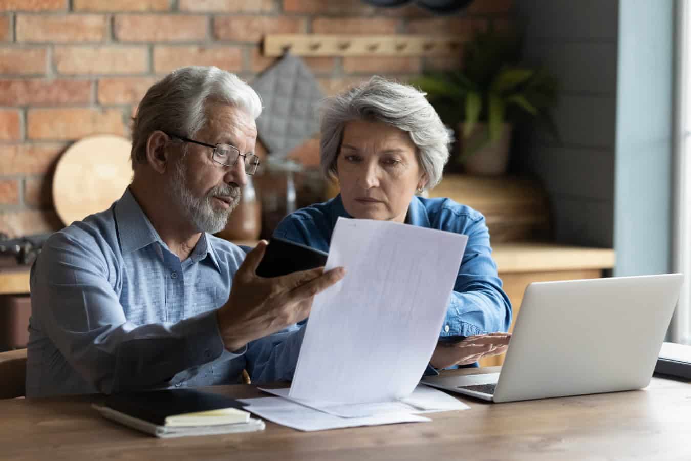 Focused worried older spouses reading financial documents checking bills