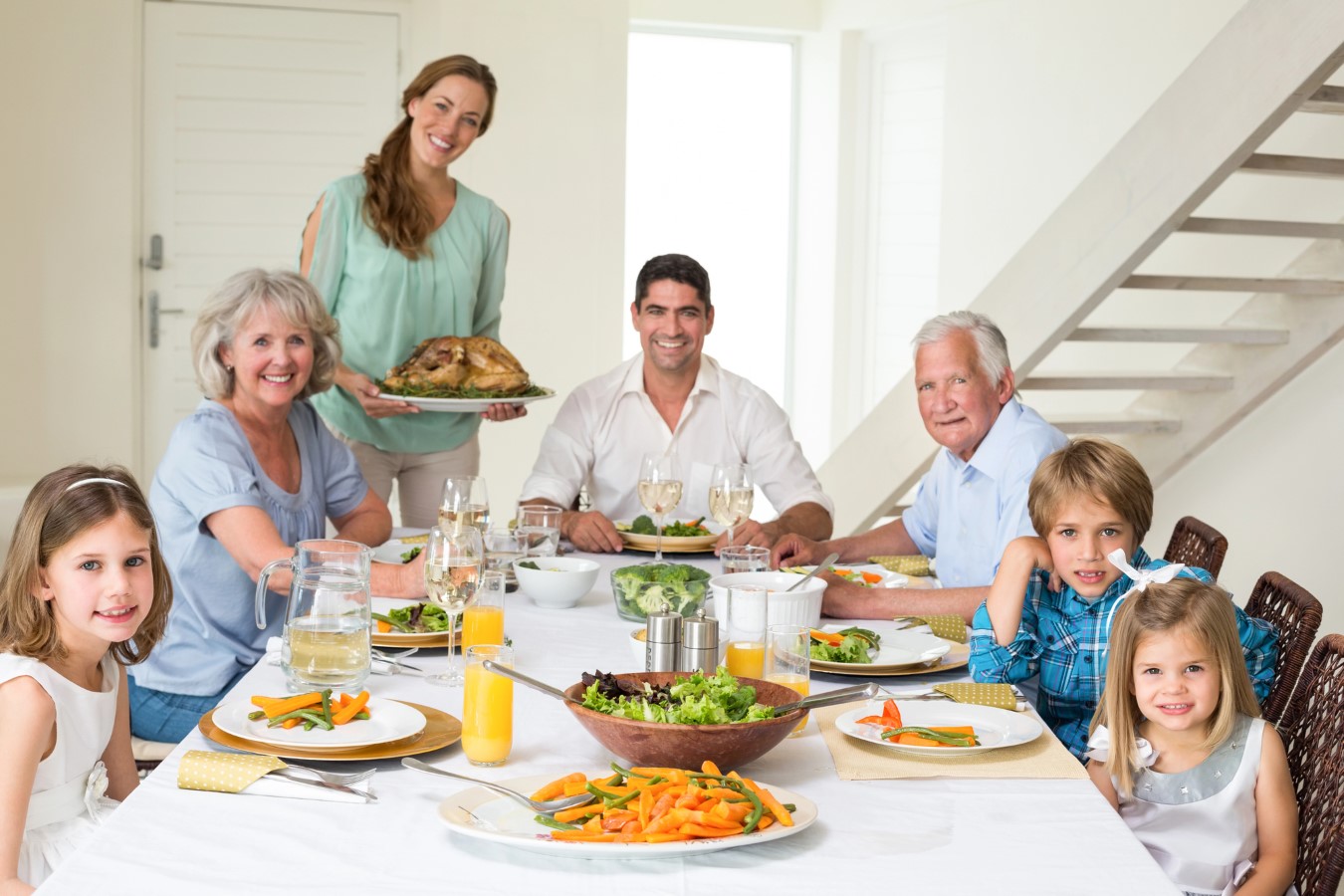 Retirement Dreams on Hold as 73% of the Sandwich Generation Support Parents and Adult Kids, Survey Finds 1 Multi-generational Family at a dining table for holiday dinner