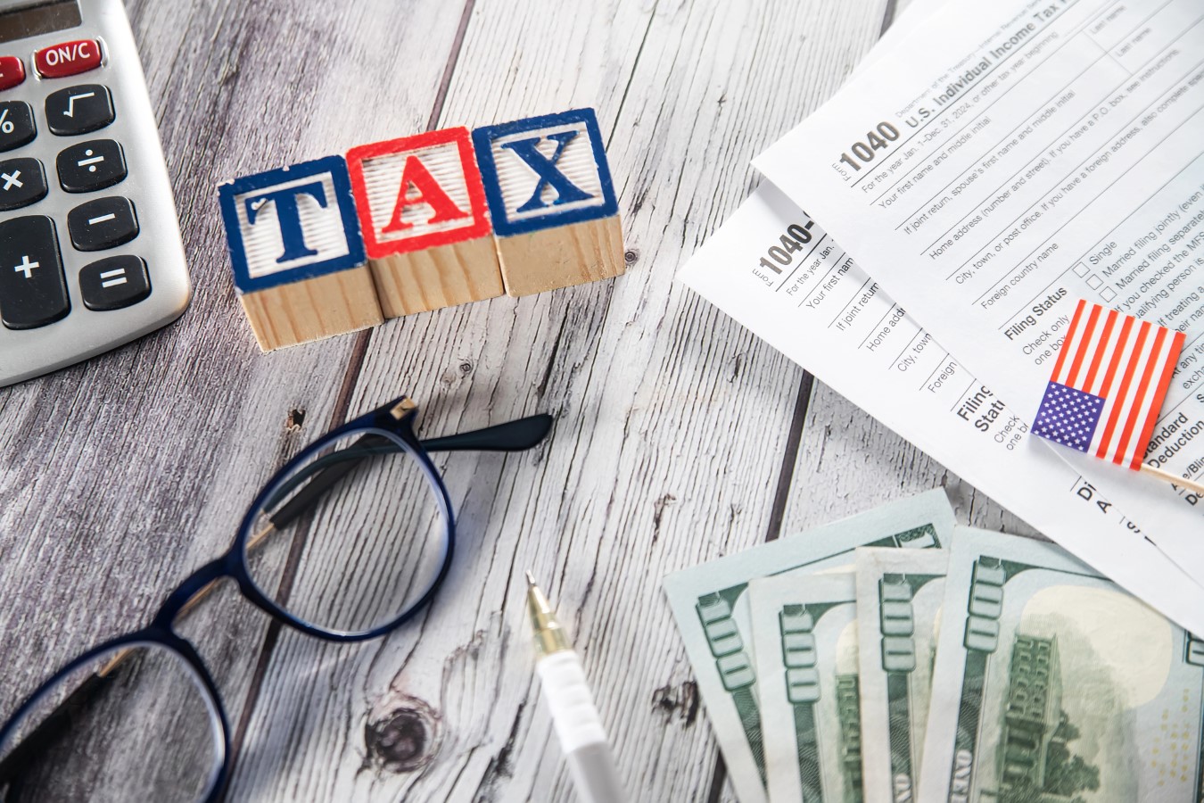 US tax form 1040, calculator and pen on wooden table