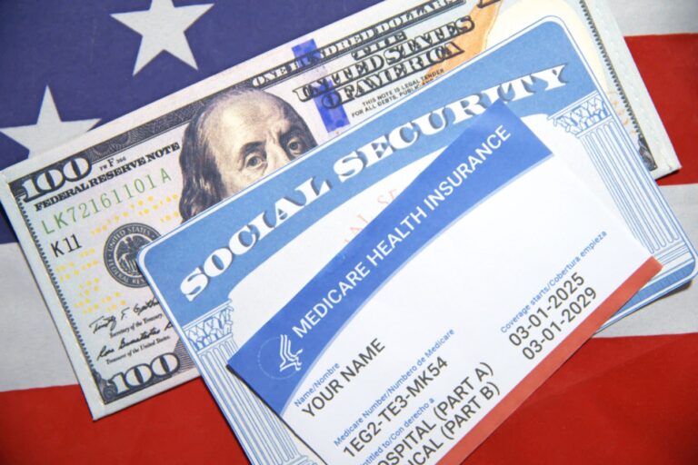 Social Security card, Medicare health insurance and 100 dollar bill placed on American flag