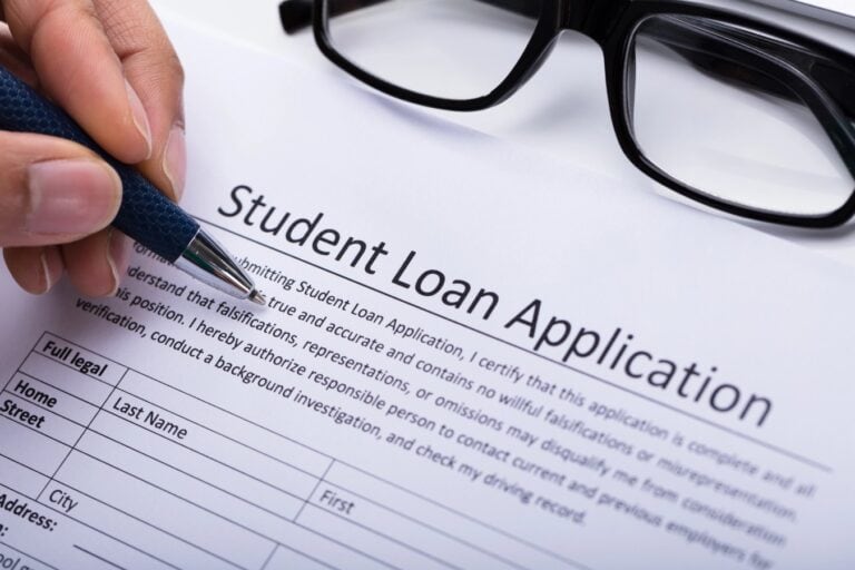 Close-up Of A Person's Hand Filling Student Loan Application Form