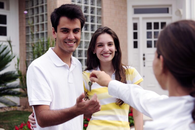 Real estate agent handing over house key to home buyers