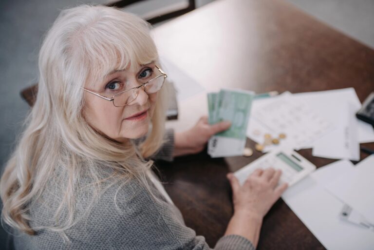 Senior woman sitting at table counting retirement funds