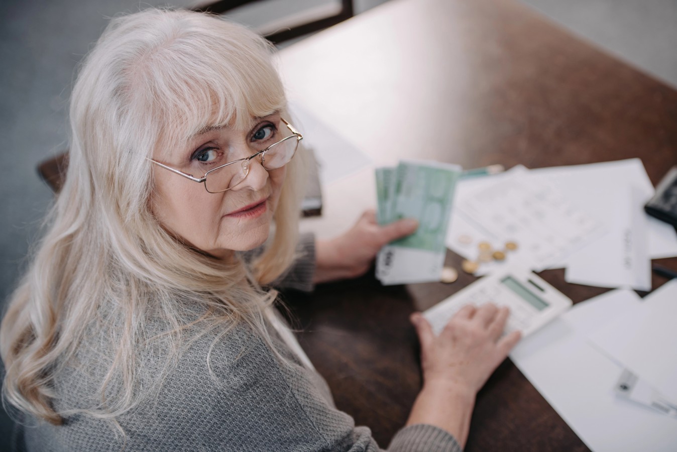 Senior woman sitting at table counting retirement funds